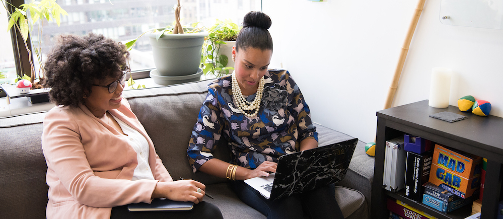 Two women of color working together on a laptop