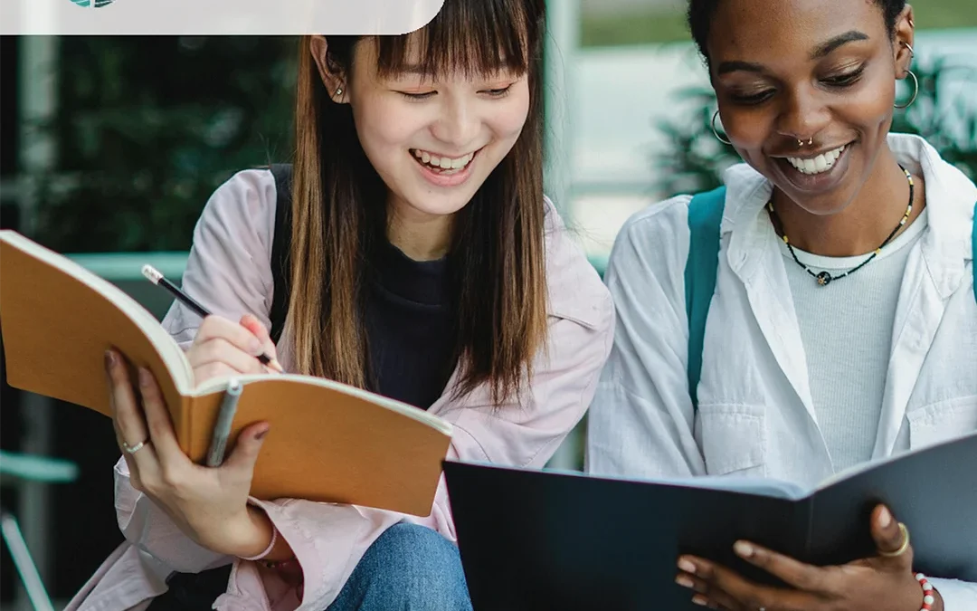 Two educators smiling and reviewing printed materials together in a learning environment