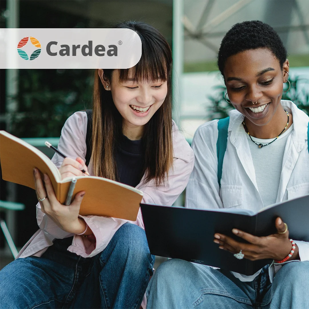 Two educators smiling and reviewing printed materials together in a learning environment