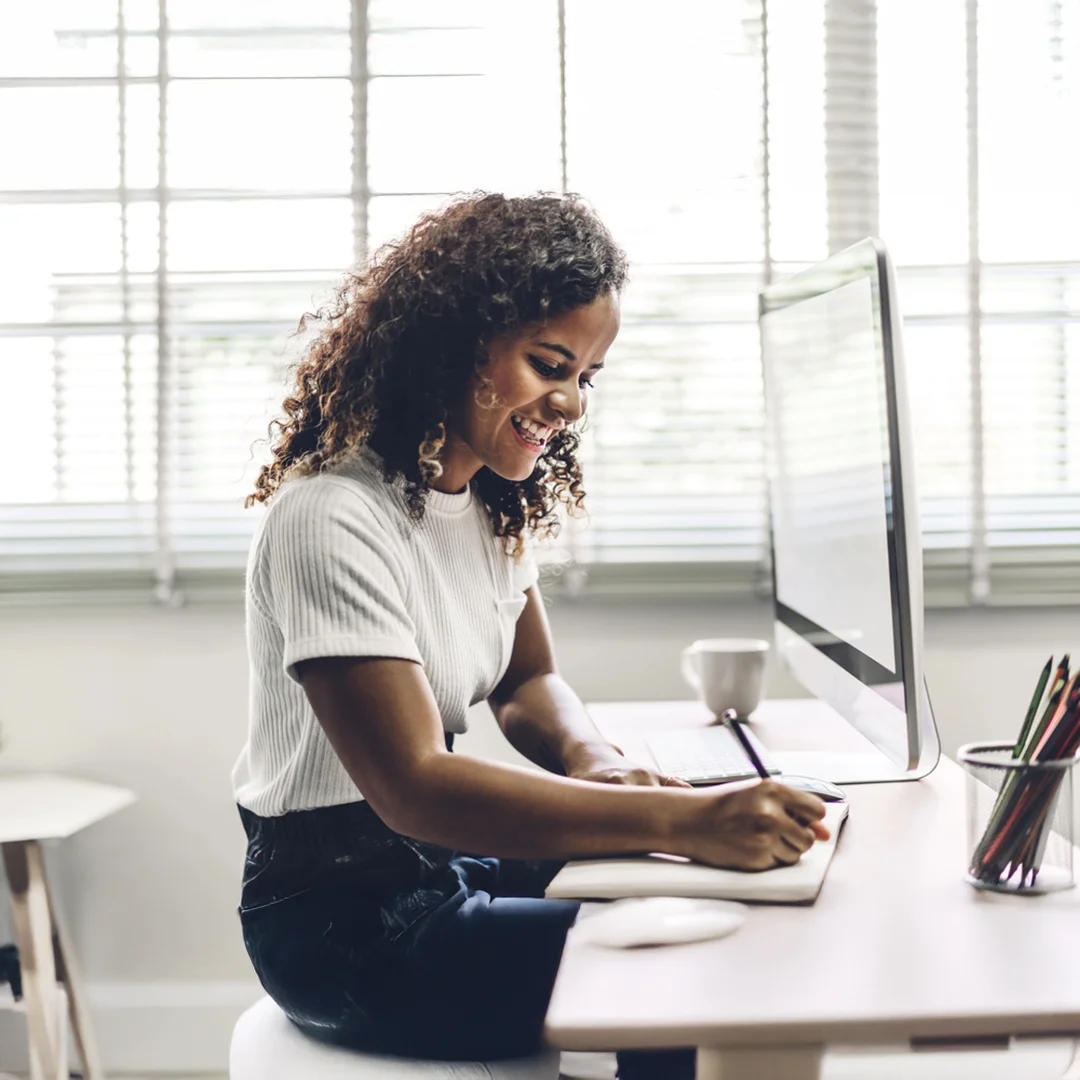 Woman Working At Desk With Computer And Notebook