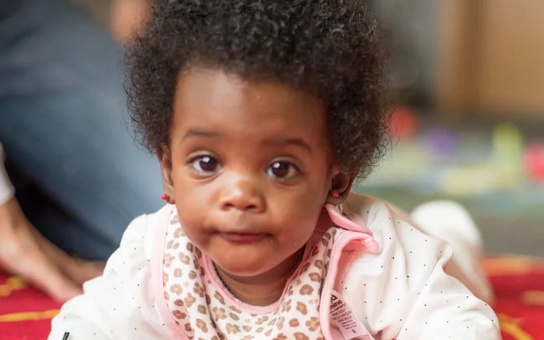 Infant lying on a colorful mat during early childhood development activity in a supportive care setting