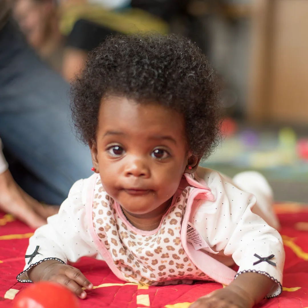 Infant lying on a colorful mat during early childhood development activity in a supportive care setting